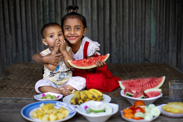 Maria, 7-letna prvošolka iz Bangladeša, in njen 1,5-letni brat Alif se pripravljata na iftar. Skupaj z družino sedita za mizo in pričakujeta obrok, pripravljen z ljubeznijo doma – preprosta, a hranljiva hrana iz svežih sestavin iz domačega vrta.